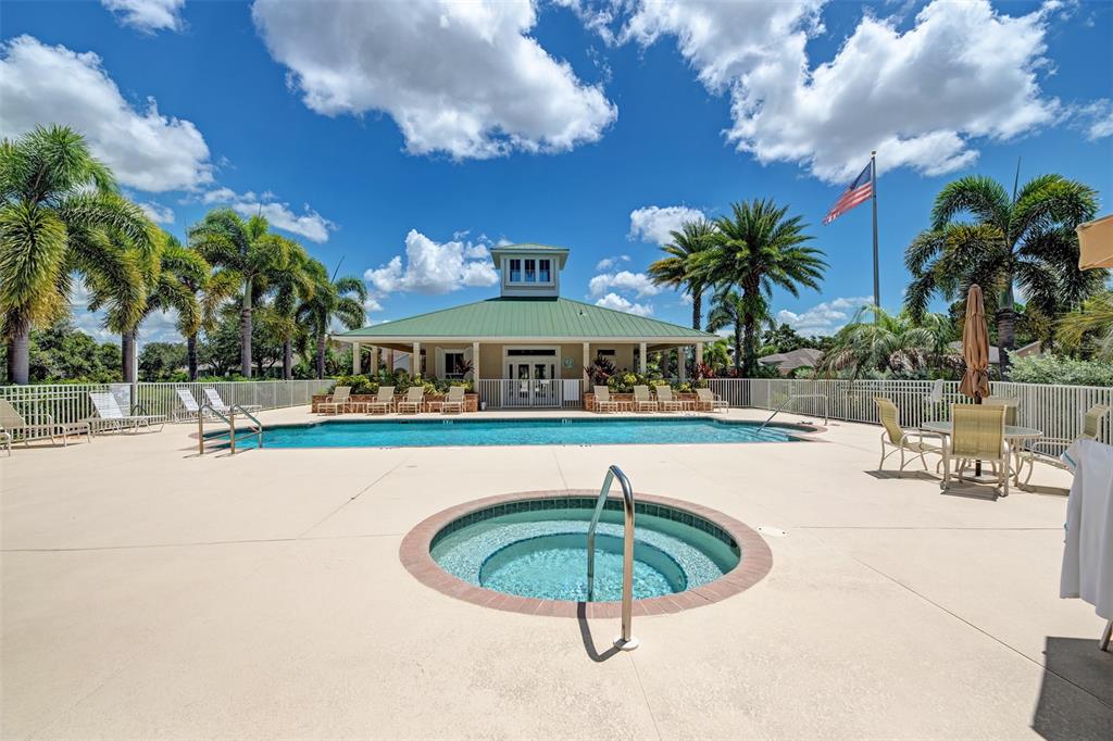 A swimming pool and hot tub sit in front of a clubhouse under a blue sky — 9082 COACHMAN DRIVE, VENICE, FL