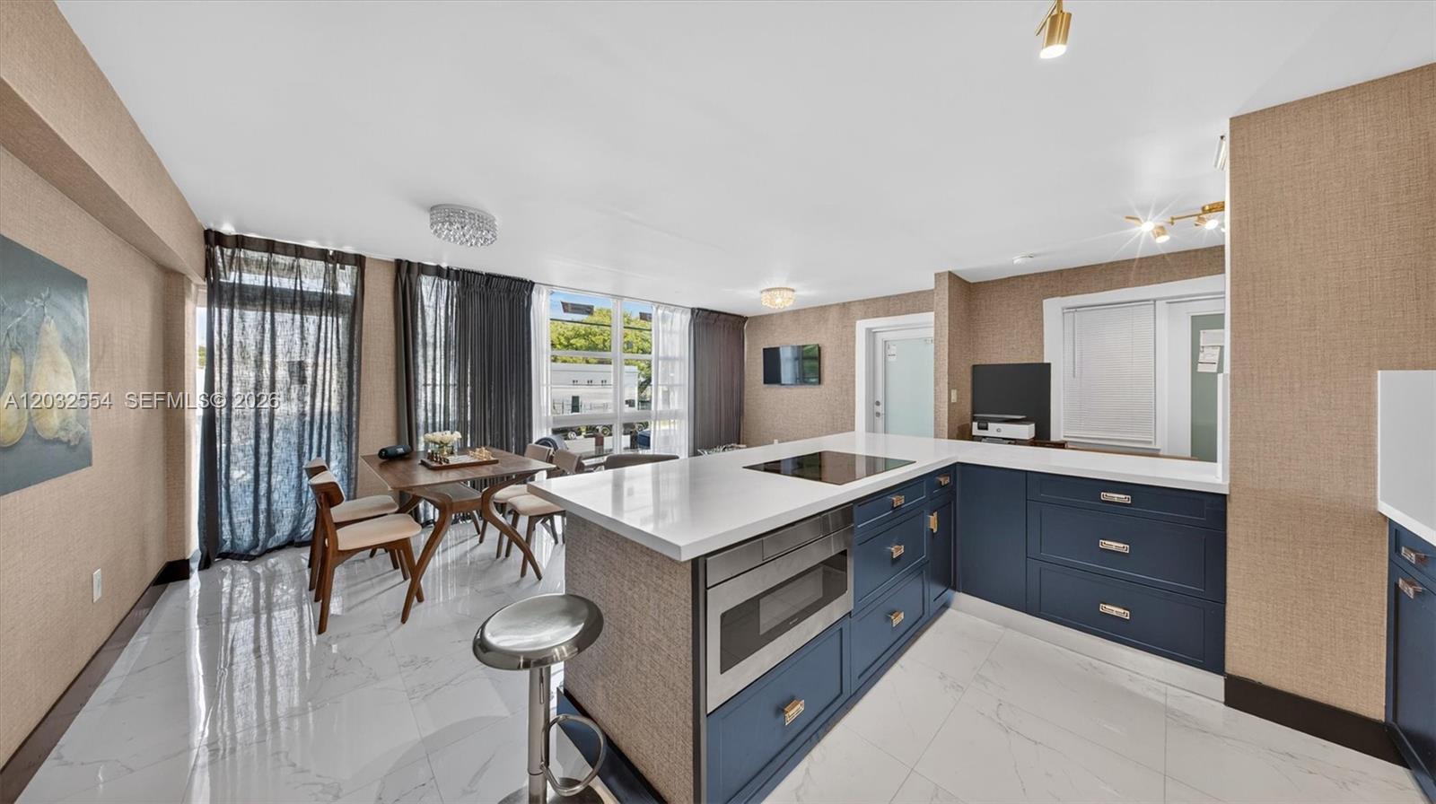 A modern kitchen features blue cabinetry, a white island countertop, and an adjacent dining area — 1400 Pennsylvania Ave # 11, Miami Beach FL 33139, MIAMI BEACH, FL