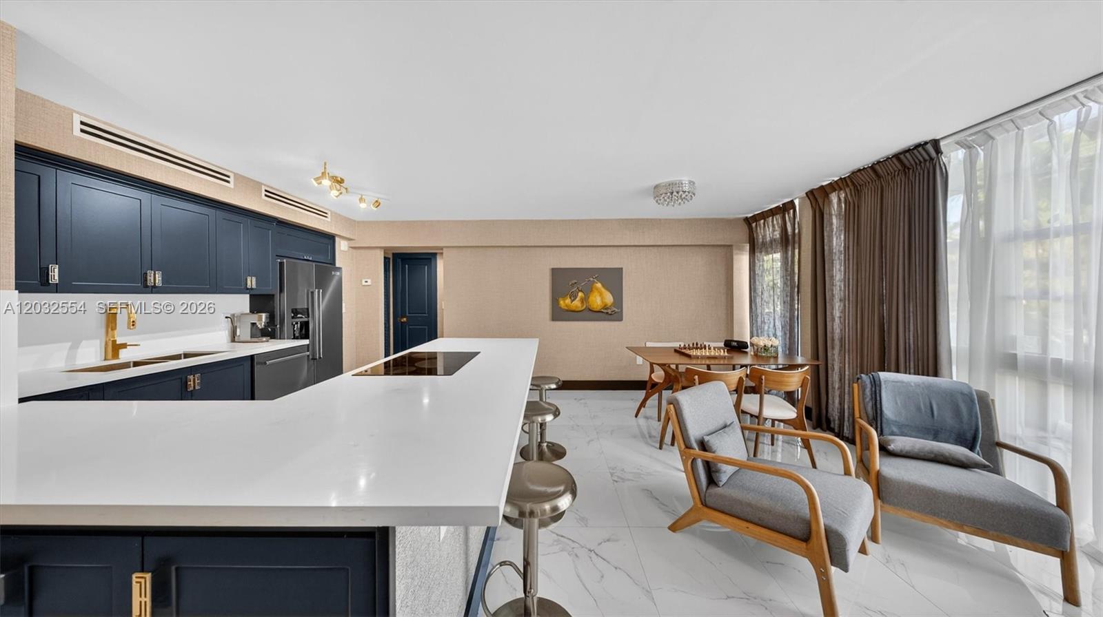 A kitchen with dark blue cabinets and a white island sits beside a dining area — 1400 Pennsylvania Ave # 11, Miami Beach FL 33139, MIAMI BEACH, FL