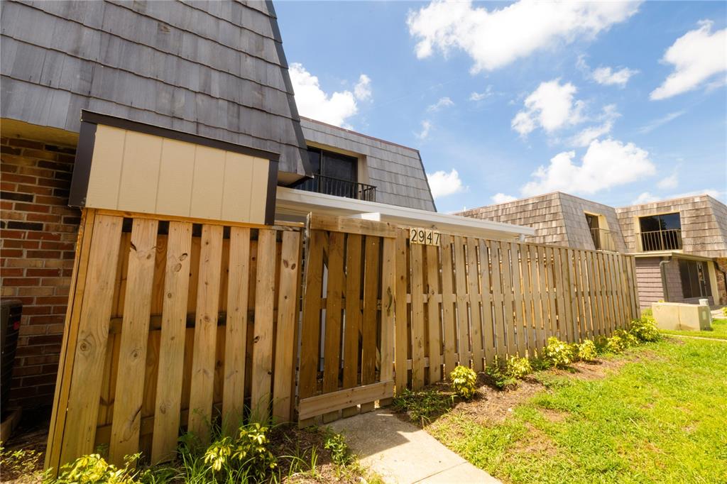 A wooden fence encloses a patio area in front of a multi-story residential building — 2947 POPLAR AVENUE, LEESBURG, FL
