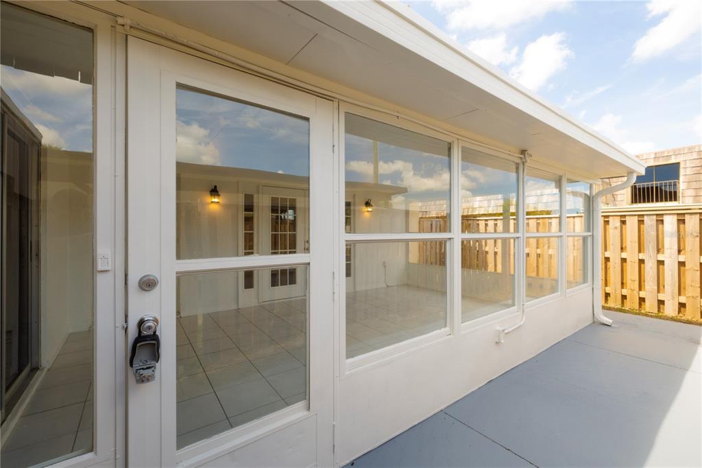A white-framed glass door leads to a sunroom with tiled floors and exterior siding — 2947 POPLAR AVENUE, LEESBURG, FL