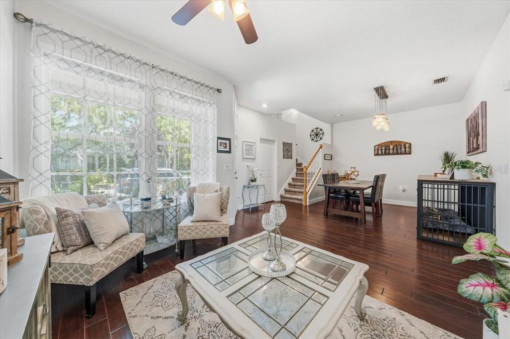 A living and dining area with dark wood floors, a glass coffee table, and stairs — 9606 ROYCE DRIVE, TAMPA, FL