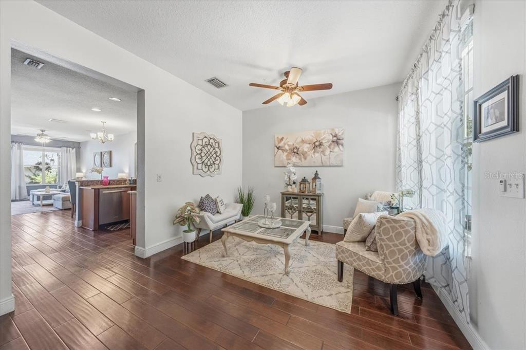 A living room features hardwood floors, a ceiling fan, and a rug under a coffee table — 9606 ROYCE DRIVE, TAMPA, FL