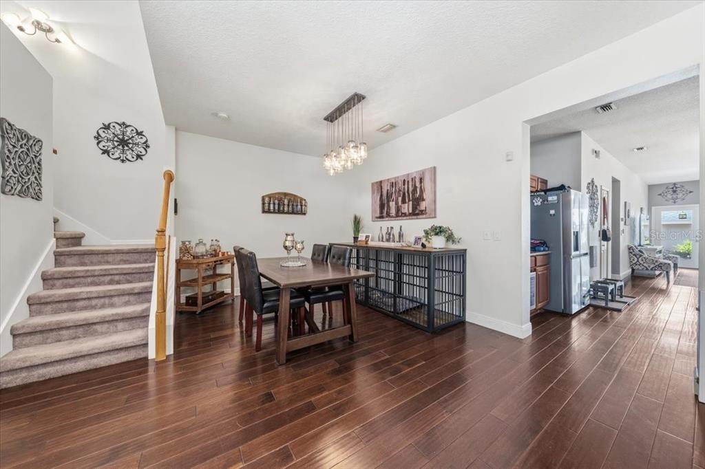 A dining area features a wooden table, dark chairs, a chandelier, and hardwood flooring — 9606 ROYCE DRIVE, TAMPA, FL