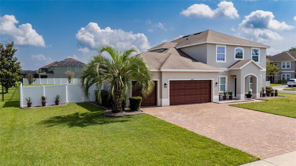A two-story suburban house features a brown garage, a palm tree, and a paved driveway — 14537 SAN LORENZO DRIVE, ORLANDO, FL
