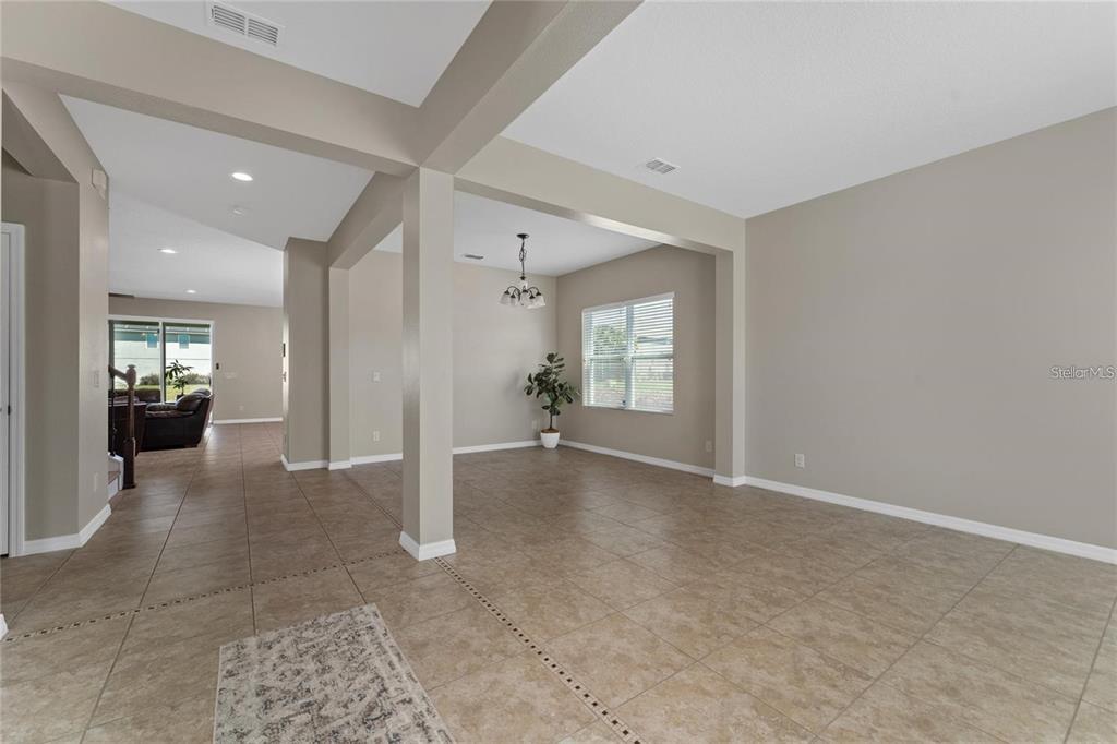 An open-concept living area features beige tile flooring, neutral walls, and a dining room chandelier — 14537 SAN LORENZO DRIVE, ORLANDO, FL