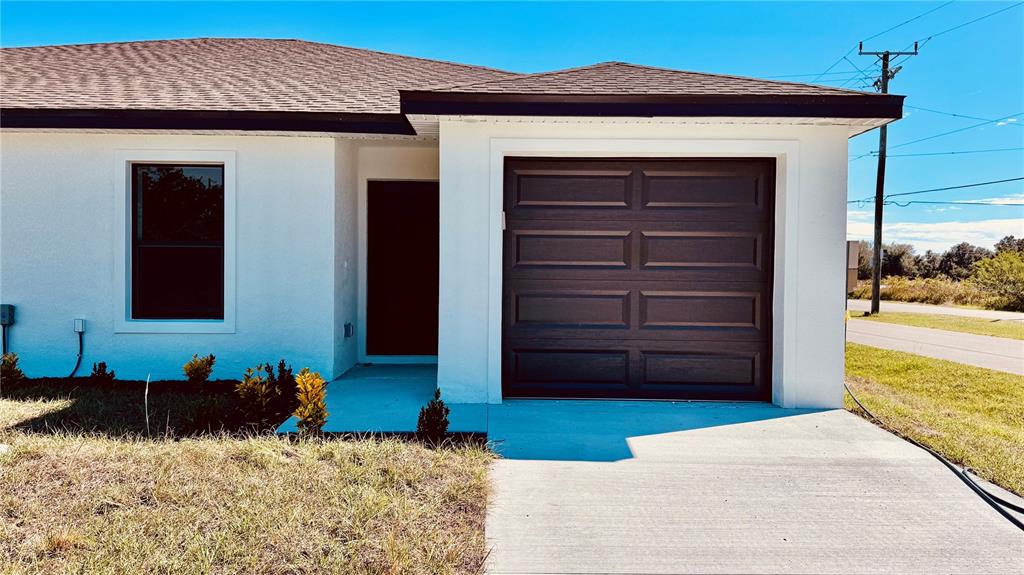 A white single-story house features a dark garage door, a front entrance, and a window — 27063 WASHINGTON STREET, PUNTA GORDA, FL