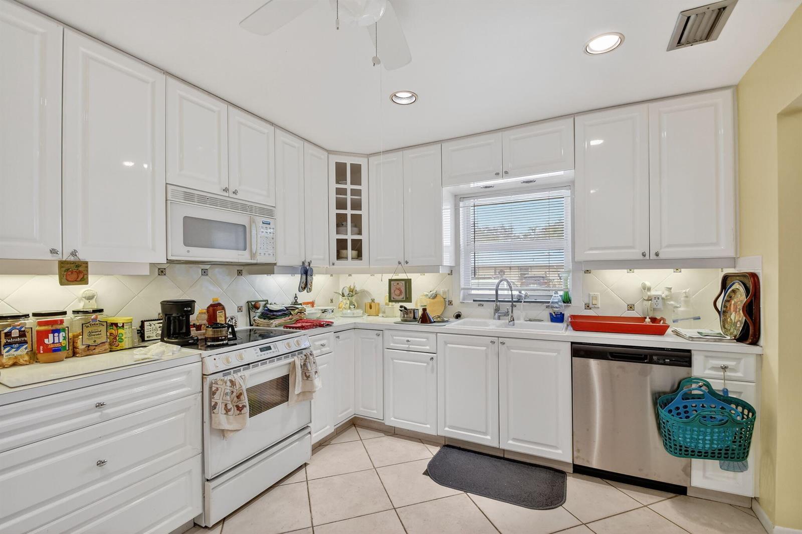 A kitchen with white cabinets, stainless steel appliances, tile flooring, and a window over the sink — 782 Nantucket Circle, FL 33467, FL