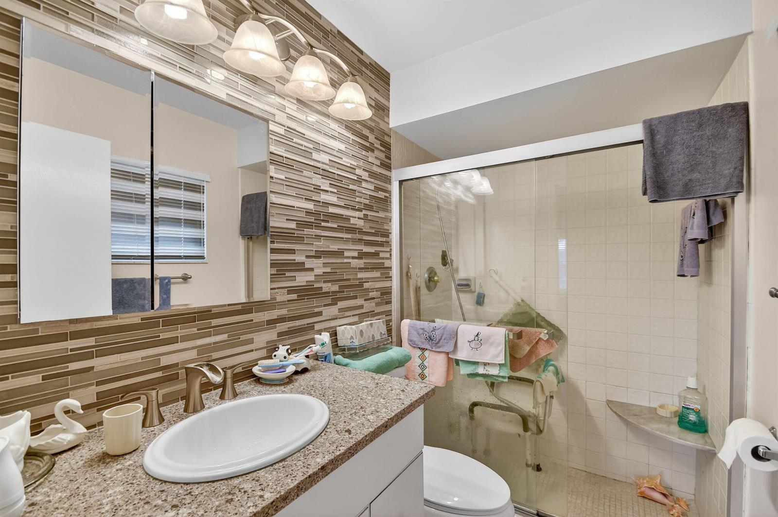 A bathroom features a granite vanity, a tiled accent wall, and a glass-enclosed walk-in shower — 782 Nantucket Circle, FL 33467, FL