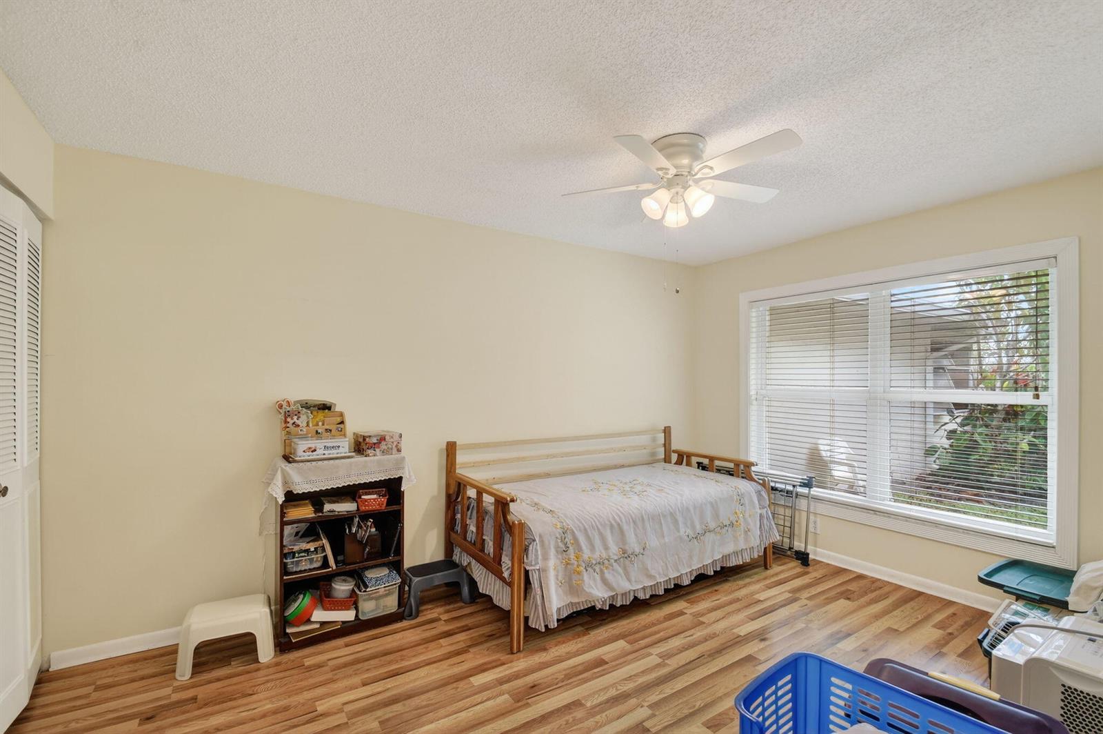 A bedroom with wood-look flooring, a daybed, a bookshelf, and a ceiling fan — 782 Nantucket Circle, FL 33467, FL