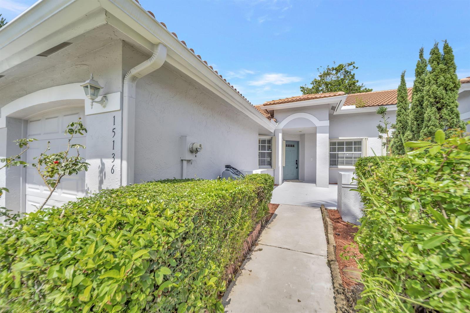 A concrete walkway leads to the front entrance of a house with a garage — 15136 W Tranquility Lake Drive, Delray Beach FL 33446, DELRAY BEACH, FL