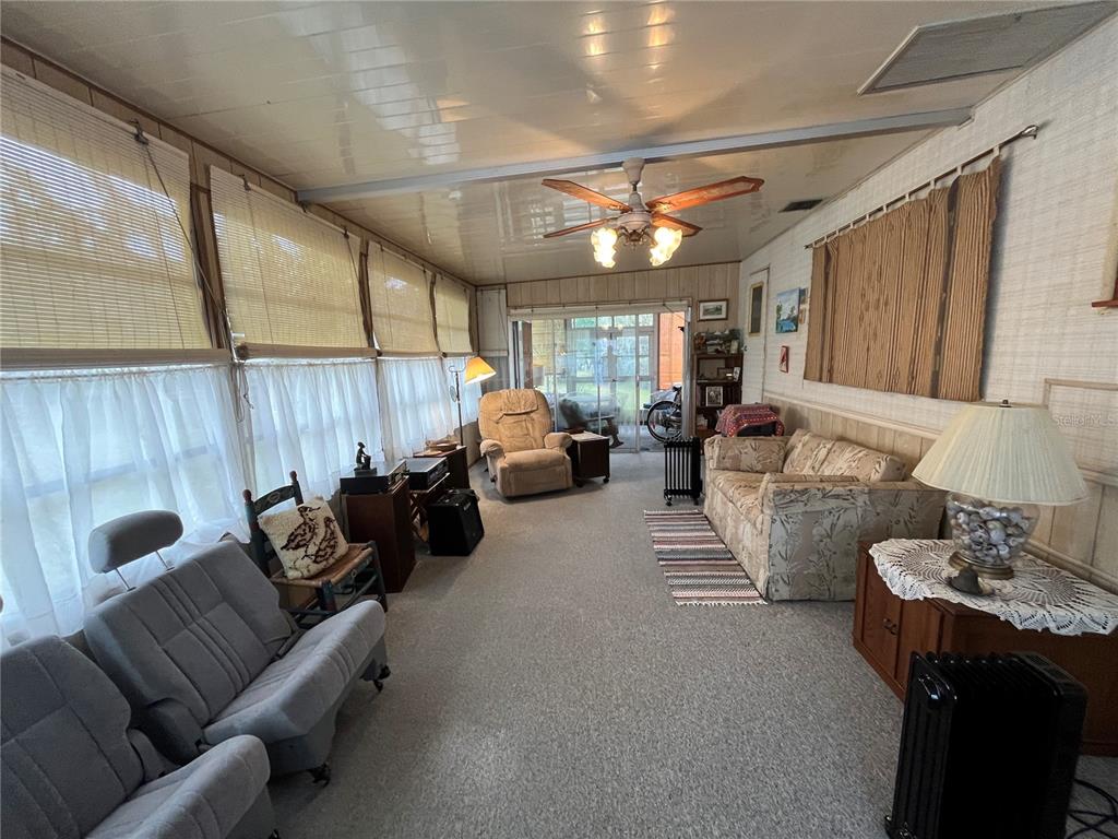 A sunroom features a ceiling fan, carpeted flooring, wood-paneled walls, and multiple seating areas — 16 GREY FOX LANE, LAKE WALES, FL