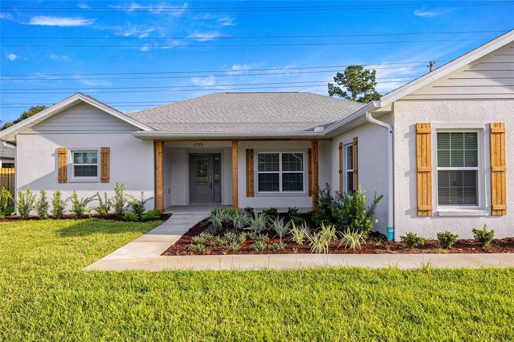 A single-story house features white stucco walls, wood-trimmed porch columns, and decorative wooden shutters — 2315 SE 31ST PLACE, OCALA, FL