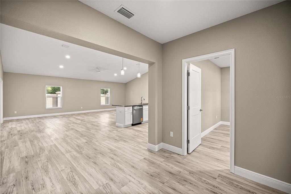 An open-concept living area with light wood-look flooring and a kitchen island with white cabinets — 2315 SE 31ST PLACE, OCALA, FL