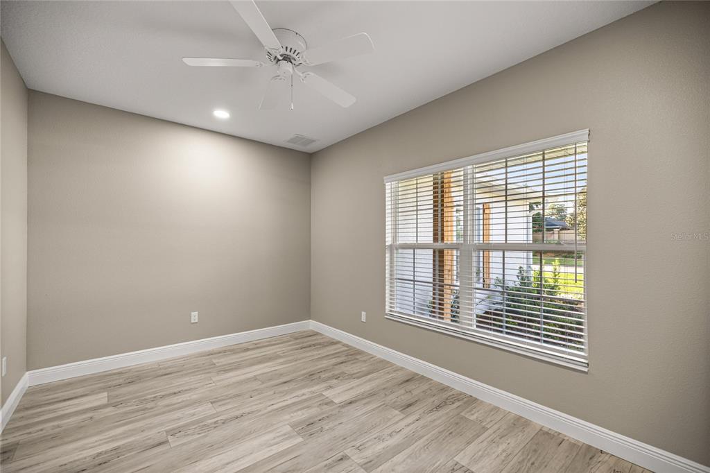 An empty room with light wood-look flooring, beige walls, a ceiling fan, and a window — 2315 SE 31ST PLACE, OCALA, FL
