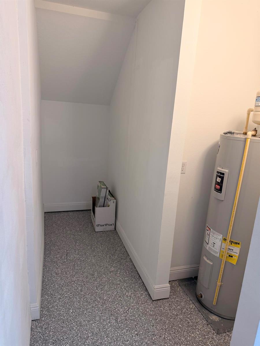 A utility closet features a water heater and a small alcove with speckled flooring — 562 Parsons Way, Deerfield Beach FL 33442, DEERFIELD BEACH, FL