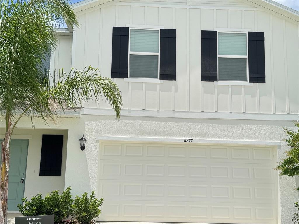 A two-story house features white vertical siding, a garage, and black window shutters — 11877 NOBLE CHASE PATH, DADE CITY, FL