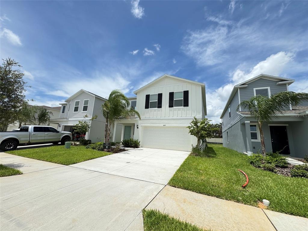 A two-story white house with a two-car garage sits between two other suburban homes — 11877 NOBLE CHASE PATH, DADE CITY, FL