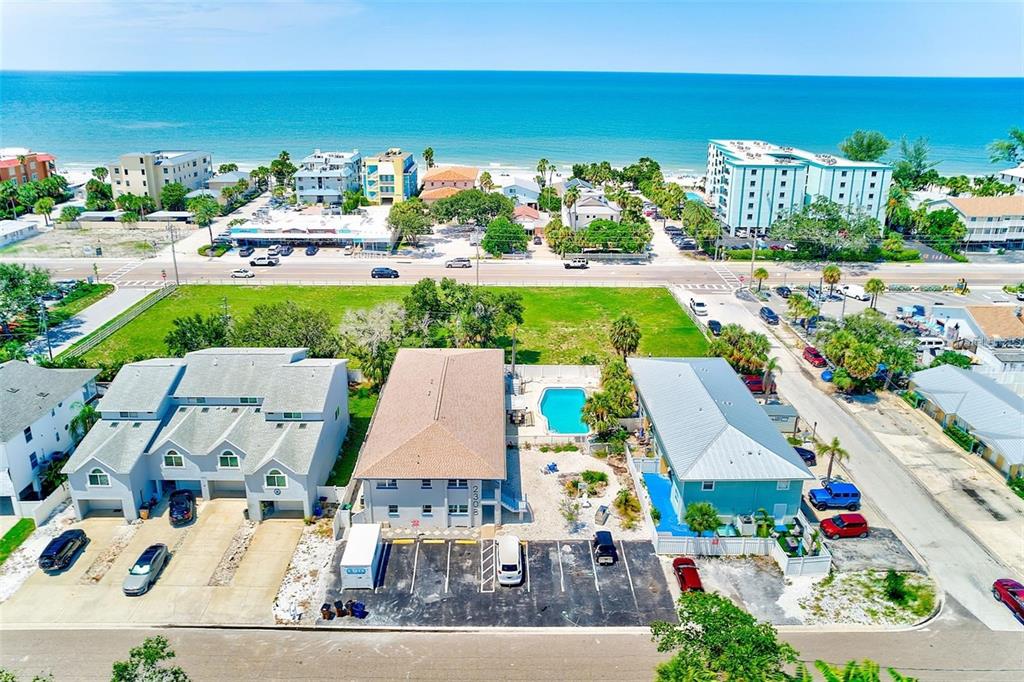 An aerial view shows three multi-story buildings near a beach with a swimming pool — 2308 1ST STREET UNIT 1, INDIAN ROCKS BEACH, FL