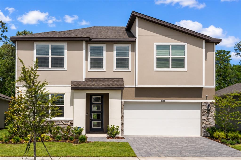A two-story house with a beige stucco exterior, stone accents, and a two-car garage — 12918 PROMISE PLACE, ORLANDO, FL