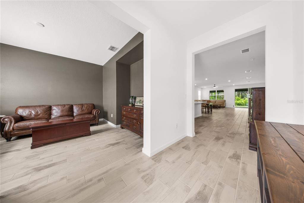 A living room with a brown leather sofa and tile flooring opens into a large kitchen — 12918 PROMISE PLACE, ORLANDO, FL
