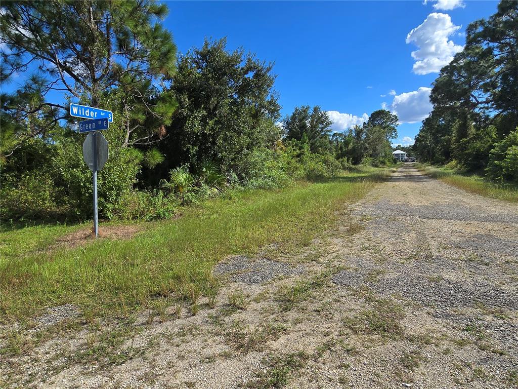 A gravel road intersection features a street sign for Wilder Avenue and Green Street — 423 WILDER AVENUE S, LEHIGH ACRES, FL