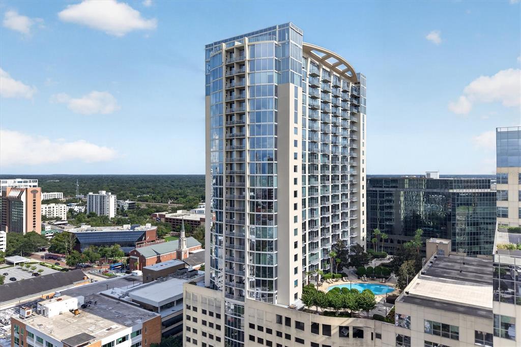 An aerial view of a tall, modern glass and concrete residential high-rise building with balconies — 155 S COURT AVENUE UNIT 2514, ORLANDO, FL