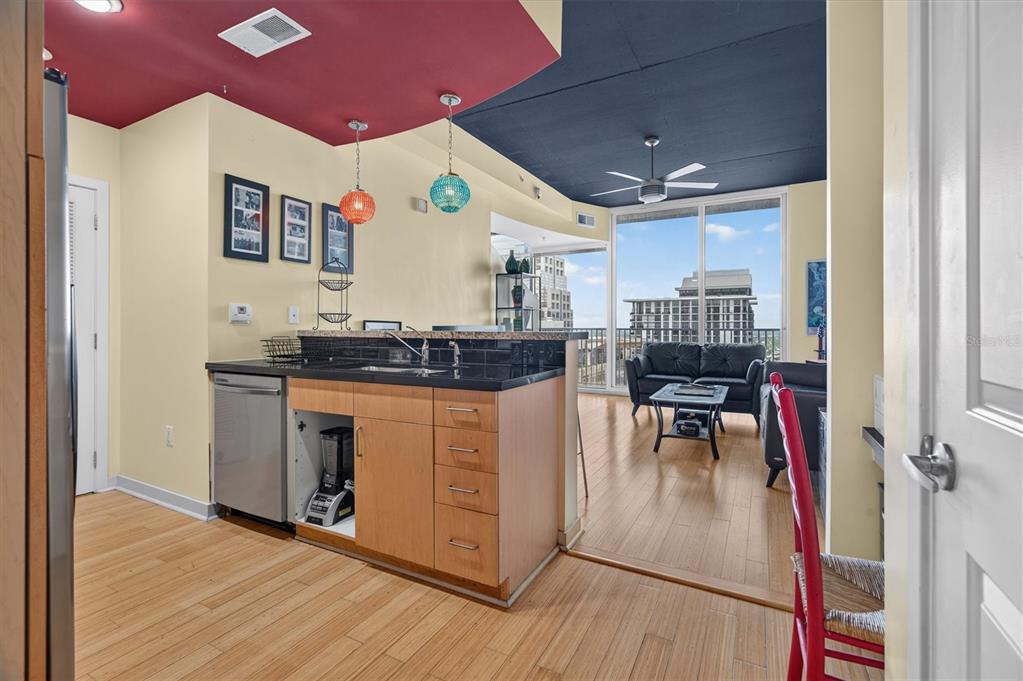 A kitchen with light wood cabinets and black countertops opens into a living room area — 155 S COURT AVENUE UNIT 2514, ORLANDO, FL