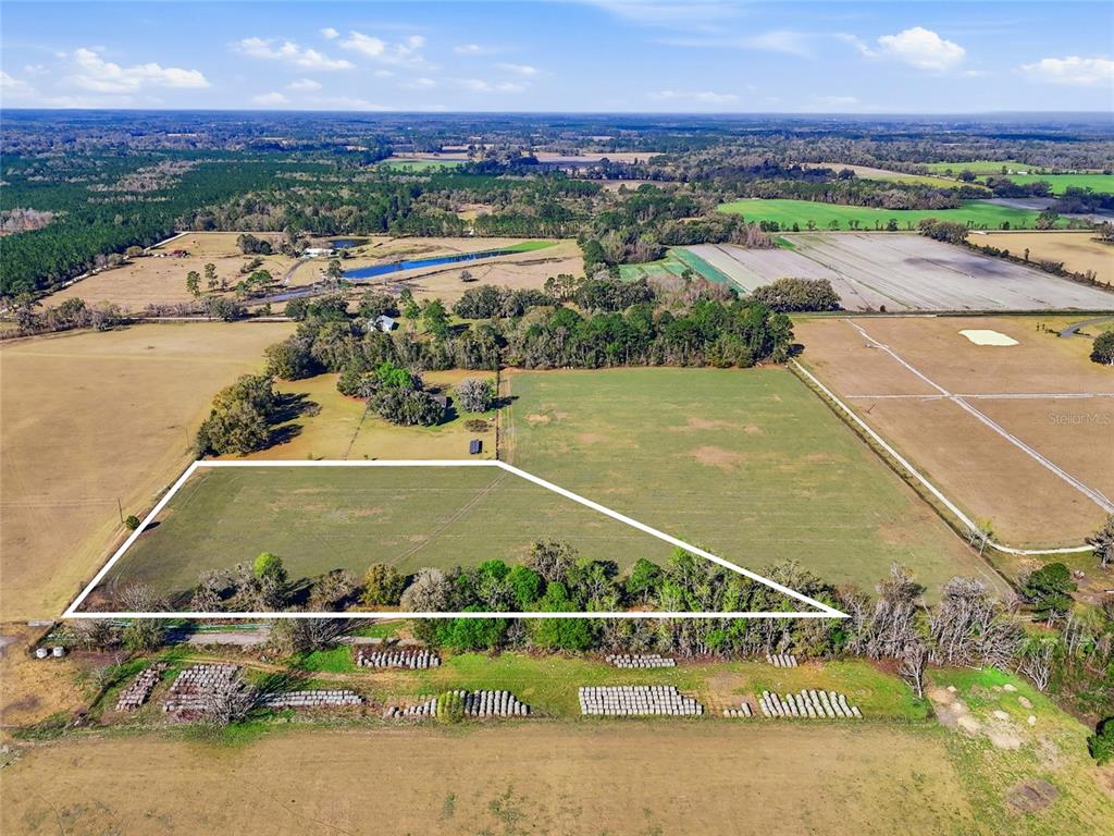 An aerial view shows a large, fenced-in grassy field outlined in white — NW COUNTY RD 239, ALACHUA, FL