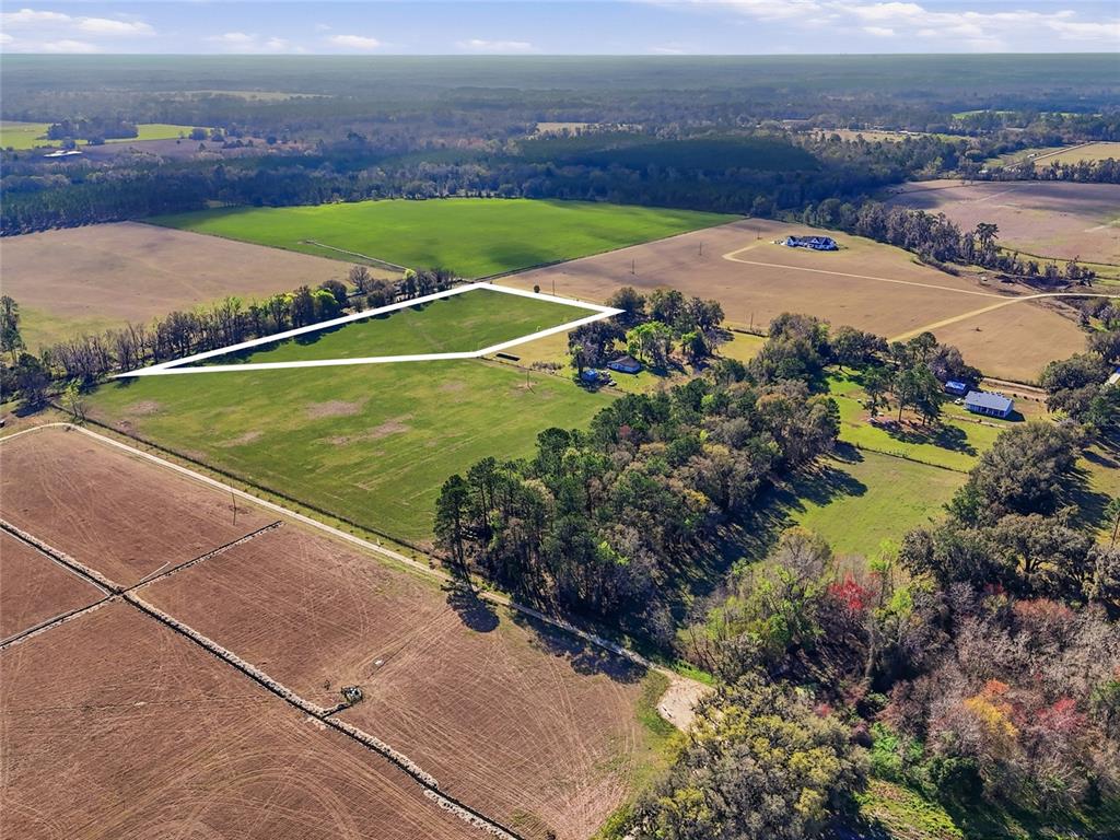 An aerial view shows a large, open grassy field outlined in white within a rural landscape — NW COUNTY RD 239, ALACHUA, FL