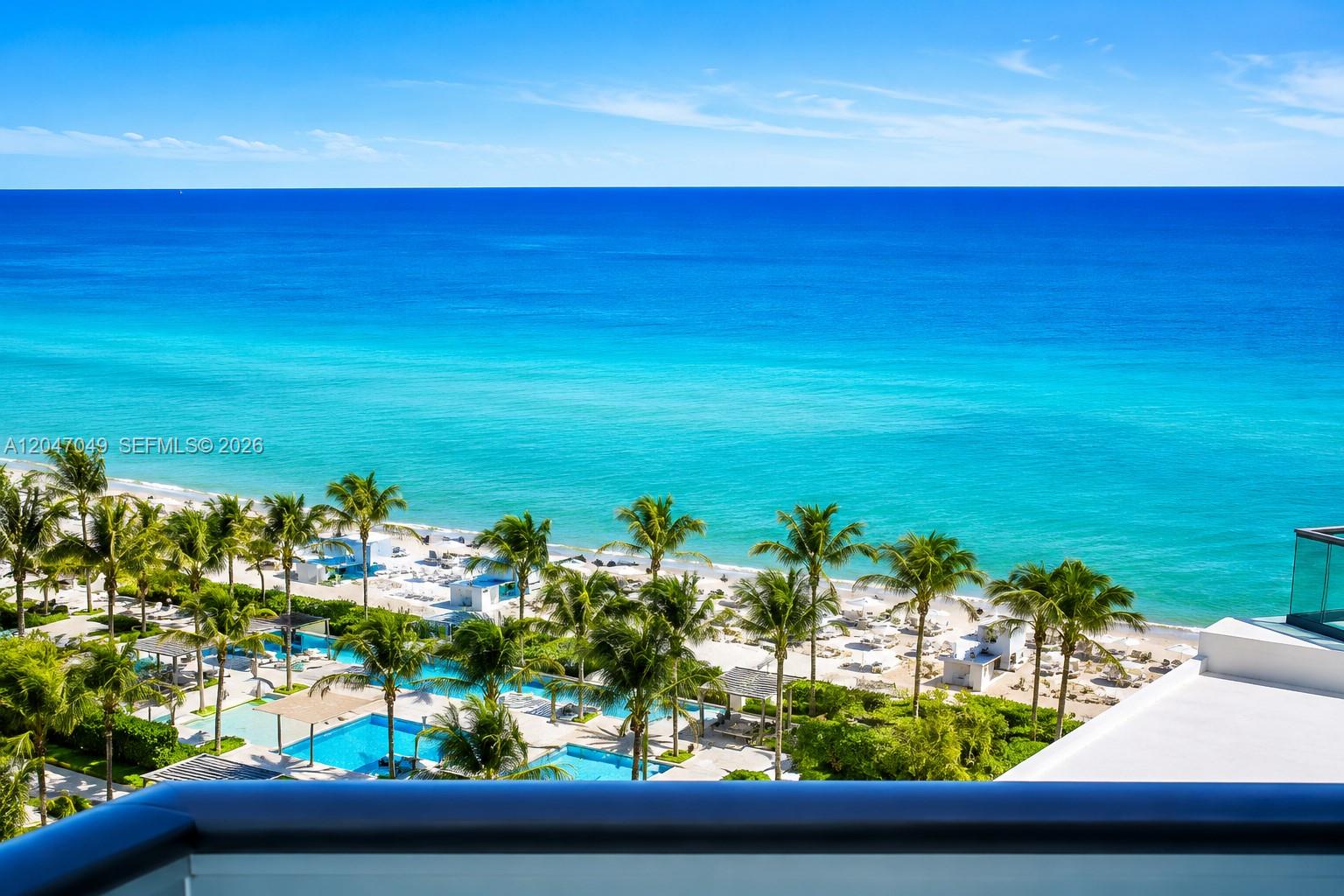 An elevated view shows a tropical beach with palm trees, swimming pools, and ocean — 4001 S Ocean Dr # 11M, Hollywood FL 33019, HOLLYWOOD, FL