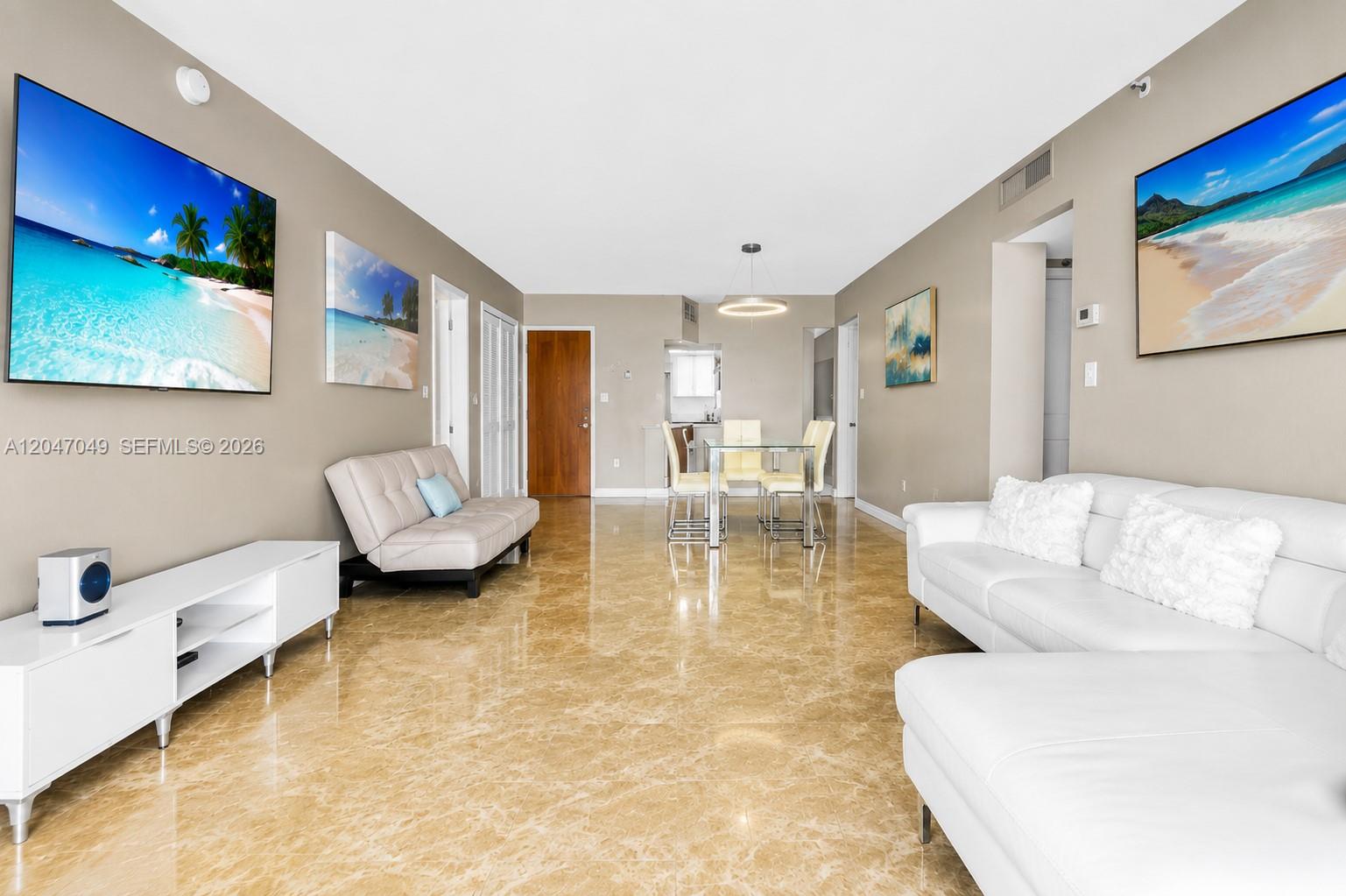 This living and dining area features beige tile floors, white furniture, and beach-themed wall art — 4001 S Ocean Dr # 11M, Hollywood FL 33019, HOLLYWOOD, FL