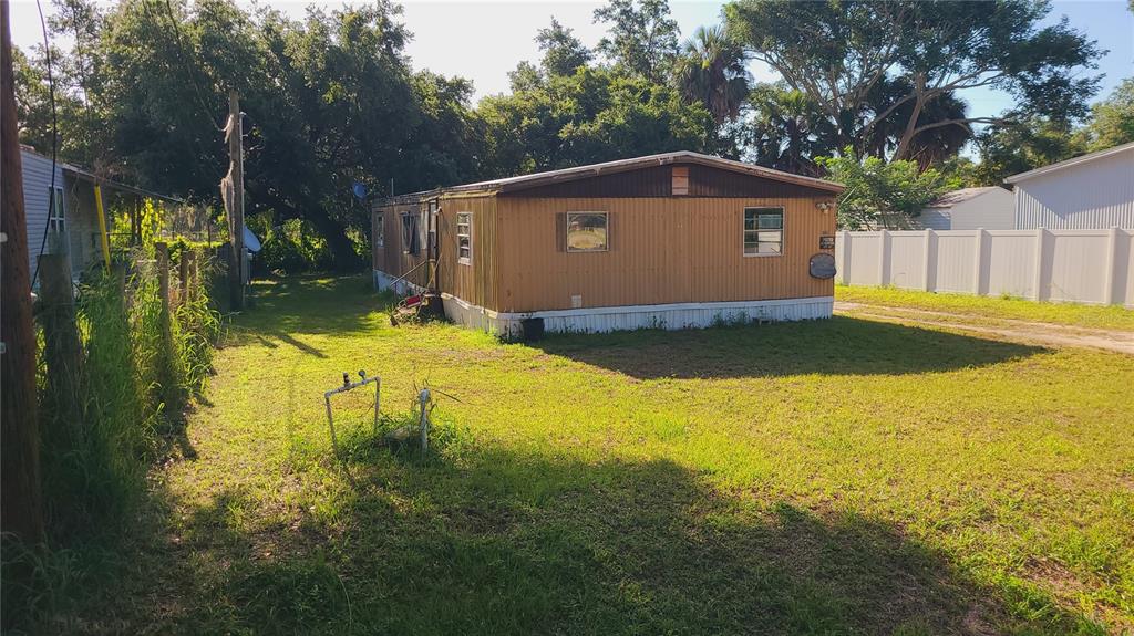 A single-story mobile home with tan metal siding sits on a grassy lot — 1683 MAGNOLIA LANE, KISSIMMEE, FL