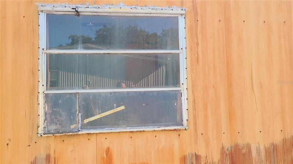 A weathered orange exterior wall features a single rectangular window with a white frame — 1683 MAGNOLIA LANE, KISSIMMEE, FL