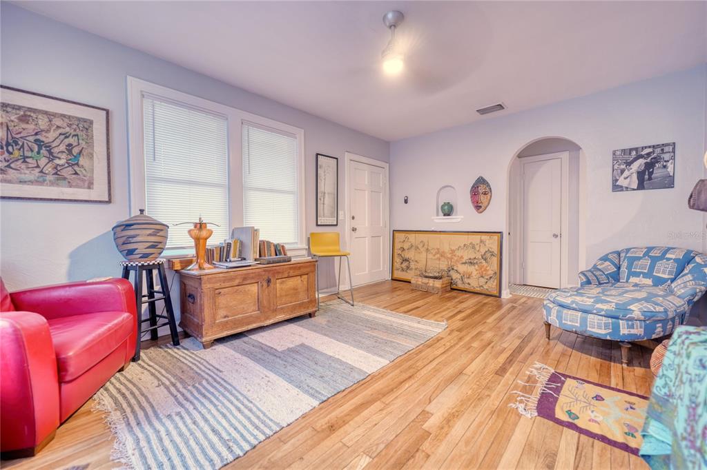A living room features hardwood floors, a red armchair, a blue patterned chaise, and art — 735 26TH AVENUE S, ST PETERSBURG, FL