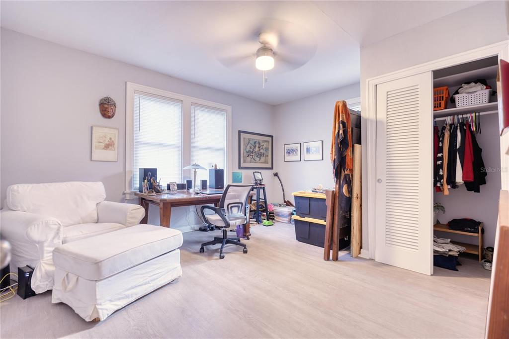 A home office features a white armchair, a wooden desk, and an open closet — 735 26TH AVENUE S, ST PETERSBURG, FL