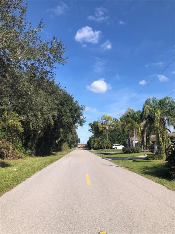 A paved residential street lined with trees and palm trees under a blue sky — 1197 EPPINGER DRIVE, PORT CHARLOTTE, FL