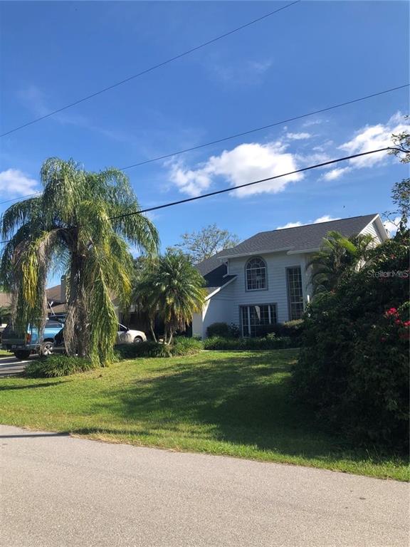A two-story house with white siding and a dark roof sits behind a grassy lawn — 1197 EPPINGER DRIVE, PORT CHARLOTTE, FL