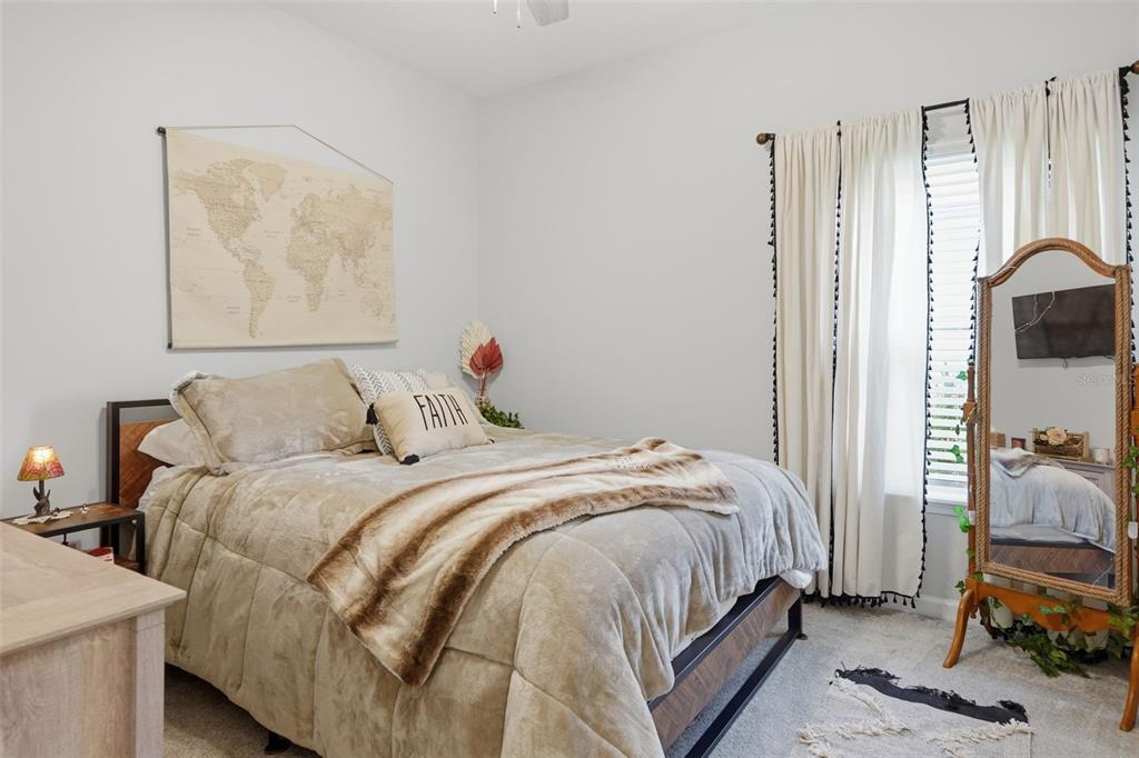 A bedroom features a bed with tan bedding, a world map wall hanging, and a mirror — 500 GRAND LANDINGS PARKWAY, PALM COAST, FL