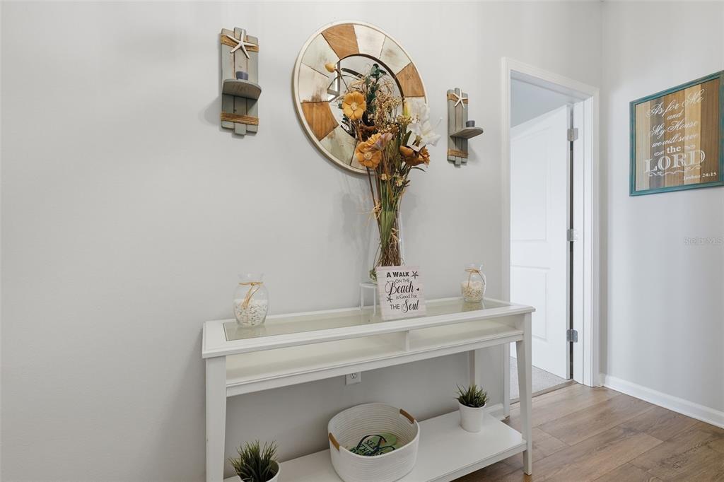 A white console table sits against a wall decorated with a mirror and wall sconces — 500 GRAND LANDINGS PARKWAY, PALM COAST, FL