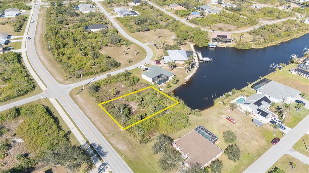 An aerial view shows a vacant, rectangular lot outlined in yellow next to a canal — 14386 INGRAHAM BOULEVARD, PORT CHARLOTTE, FL
