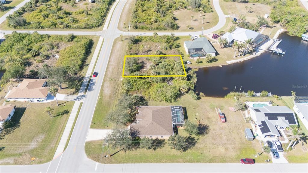 An aerial view shows a vacant, rectangular residential lot situated between two houses and water — 14386 INGRAHAM BOULEVARD, PORT CHARLOTTE, FL