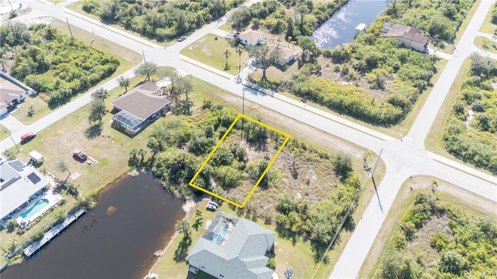 An aerial view shows a vacant, rectangular lot outlined in yellow near a canal — 14386 INGRAHAM BOULEVARD, PORT CHARLOTTE, FL