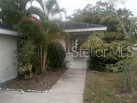 A concrete walkway leads to the covered front entrance of a single-story house with landscaping — 2508 50TH AVENUE N, ST PETERSBURG, FL