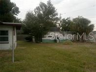 A grassy backyard features a small house on the left and a detached garage behind — 2508 50TH AVENUE N, ST PETERSBURG, FL