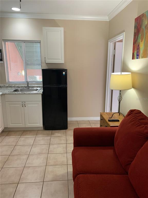 A small kitchen area with a black refrigerator and sink next to a red sofa — 2777 N POINCIANA BOULEVARD UNIT 301B, KISSIMMEE, FL