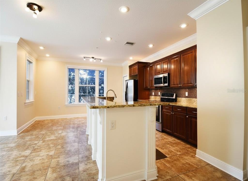 A kitchen with dark wood cabinets, granite countertops, and tile flooring features a central island — 4281 ANISSA AVENUE UNIT 11, ORLANDO, FL