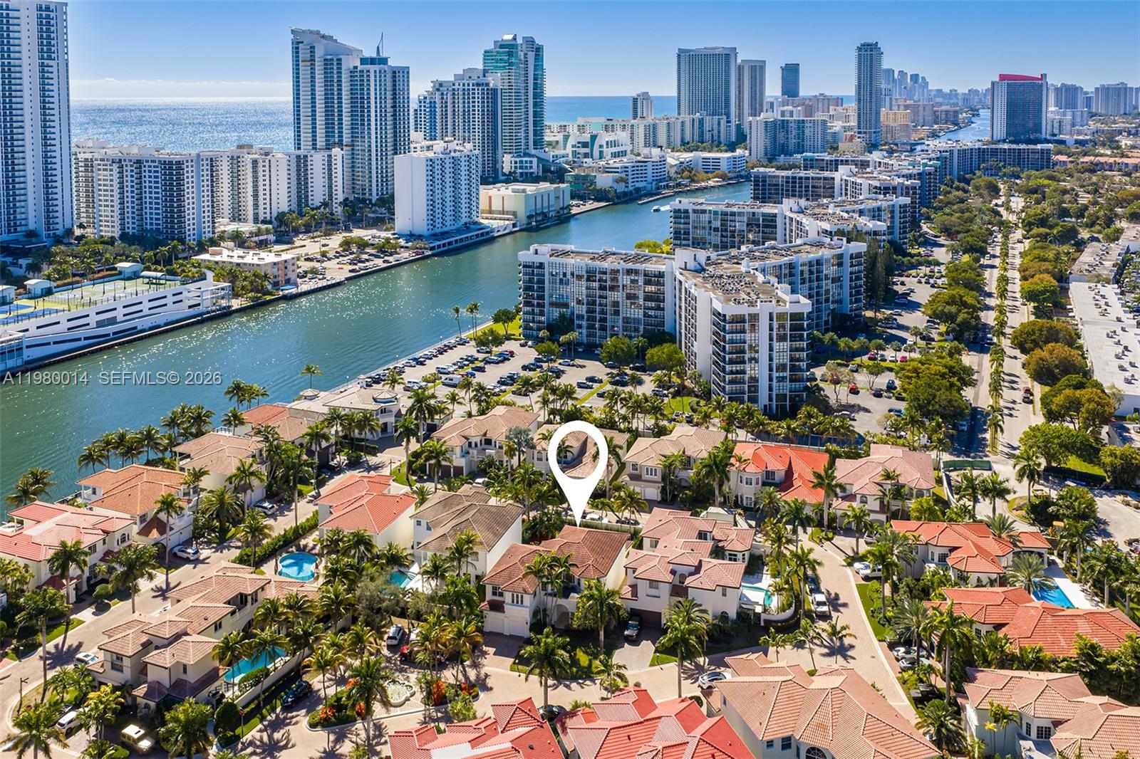 An aerial view shows a residential neighborhood with tiled roofs near a canal and skyscrapers — 822 Meridian Ln, Hollywood FL 33019, HOLLYWOOD, FL