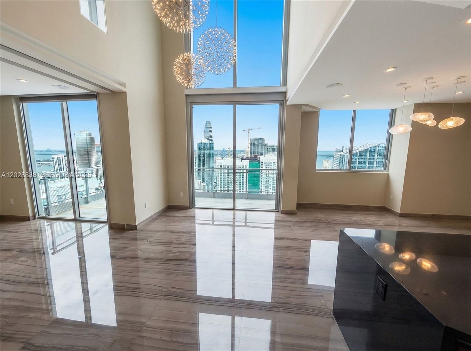 A spacious living area features floor-to-ceiling windows, polished tile floors, and modern pendant lighting — 92 SW 3rd St, Miami FL 33130, MIAMI, FL