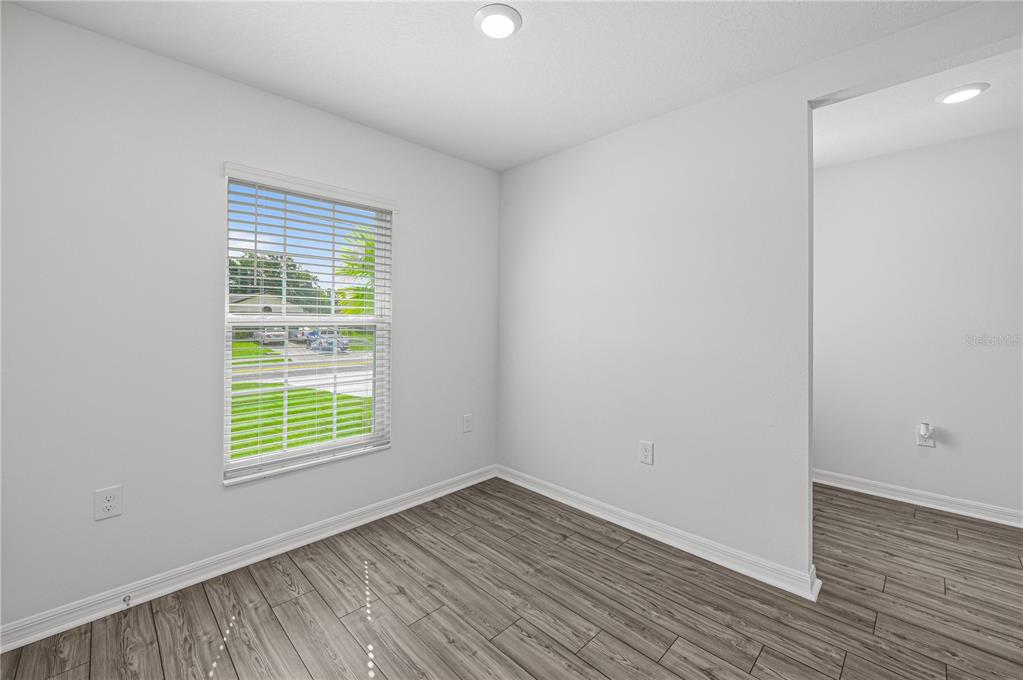 An empty room with gray wood-look flooring, white walls, and a window with blinds — 48 HERRING COURT, POINCIANA, FL